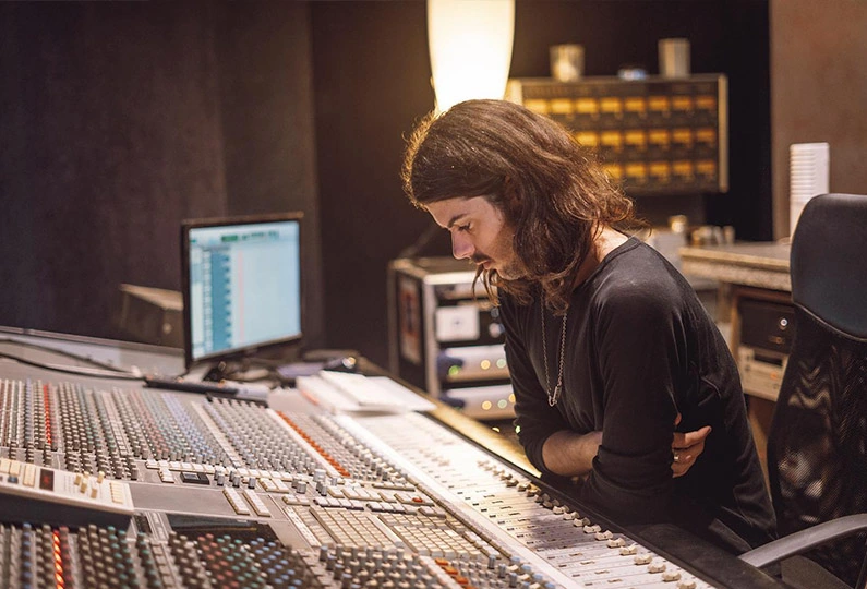 Photo of music producer Estanislao López looking at a mixing console while working in the studio